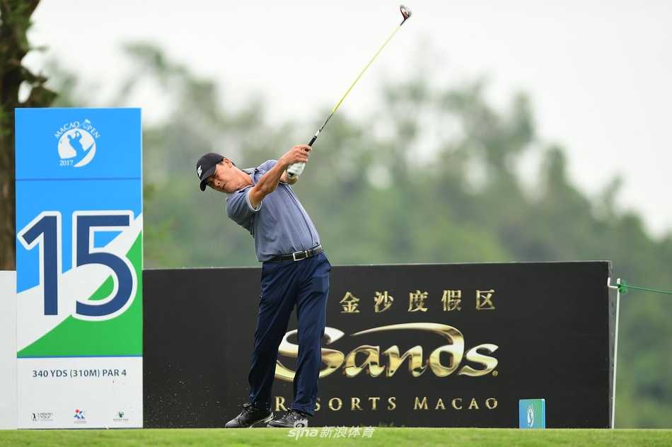 张连伟果岭上仔细研判推杆线路，背景是澳门特色的现代建筑群