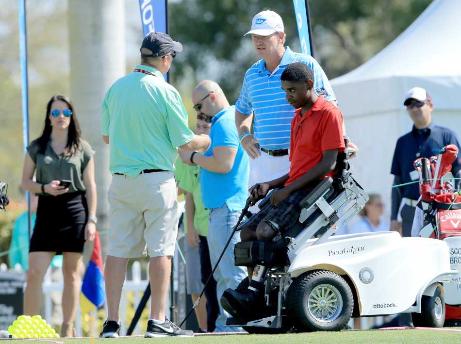 大易哥俯身耐心指导一名坐轮椅的儿童握杆，眼神专注而充满鼓励。