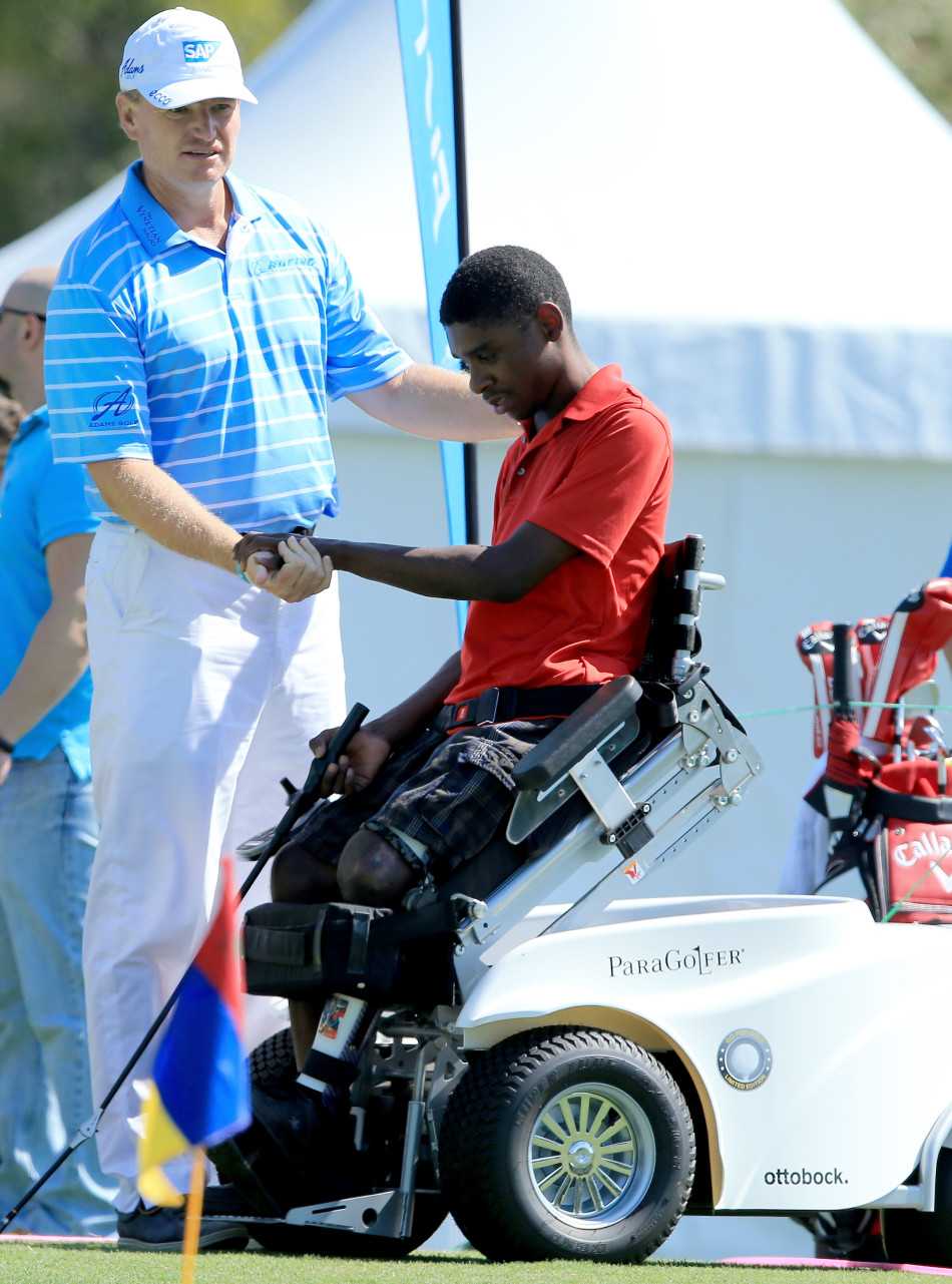 大易哥牵着一位盲童的手，让他用指尖感受高尔夫球的纹路与质地。