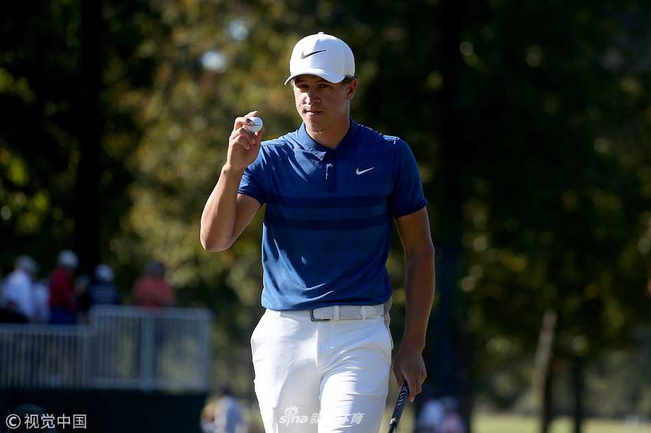 钱普在第十五洞果岭上俯身审视推杆线路，帽檐下的脸庞写满坚毅与决心