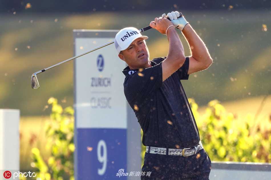 观众们穿着雨衣聚集在果岭旁的山坡上，色彩斑斓的雨具成为灰暗天气中一抹亮丽的风景