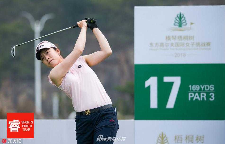 观众围在果岭边观看精彩推杆，绿草如茵的赛场与远处现代建筑相映成趣