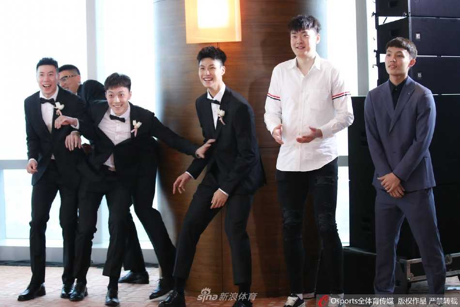 婚礼现场全景，王薪凯与妻子在舞台中央接受宾朋的祝福，背景是唯美的灯光花海，气氛热烈而浪漫。