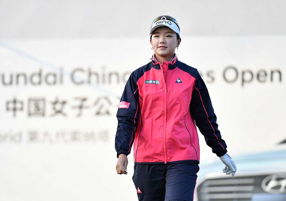 张哈娜在果岭边进行精妙的切杆，身体姿态优雅而稳定，小球应声落向洞杯。