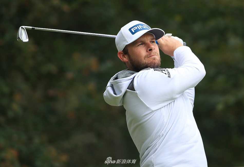 泰瑞尔·哈顿在第十八洞果岭旁凝视远方，眼神坚定，身后是经典的温特沃斯俱乐部会所