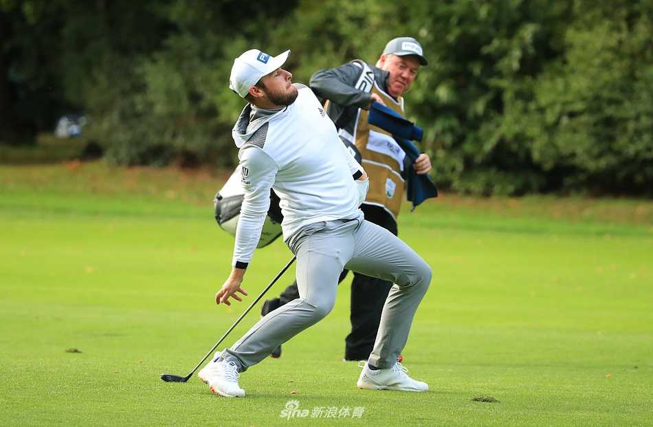 肖恩·劳瑞在树林中谨慎观察球路，阳光透过枝叶在他身上投下斑驳光影