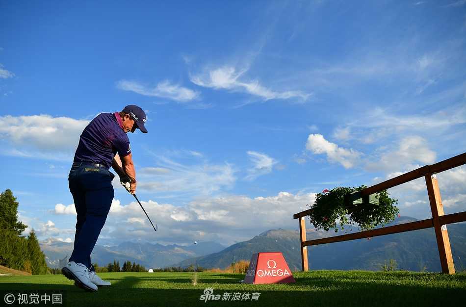 球手弯腰仔细观察果岭曲线，阳光洒在肩头，背景中古朴的木屋与远山静默相伴