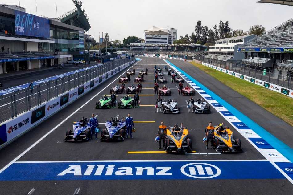 蔚蓝赛道上，黑白涂装赛车如闪电般划过弯道，扬起淡淡烟尘，背景中墨西哥城的地标建筑在热浪中微微摇曳。