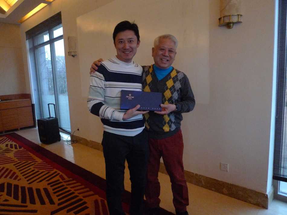 活动主题背景板前，工作人员正为嘉宾详细介绍礼盒的设计理念，众人神情专注