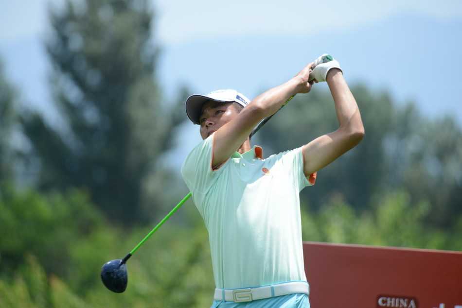 高尔夫球手在发球台上优雅开球，身体充分扭转，目光专注地望向远方的球道